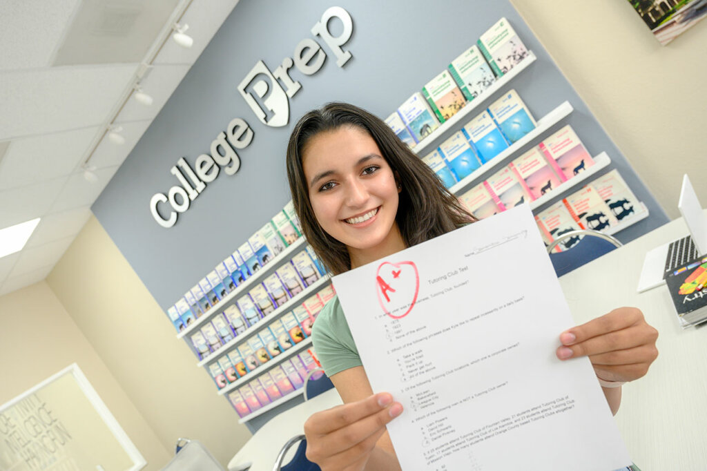 A smiling student holding an A-graded paper, symbolizing improved confidence, skills, and academic progress through tutoring.